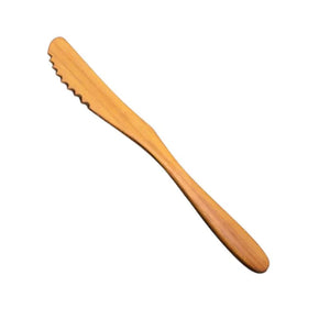 A handcrafted serrated knife made from solid teak wood, featuring a naturally sharp notched edge and a smooth ergonomic handle, ideal for slicing soft breads, cakes, or cheeses without sticking.