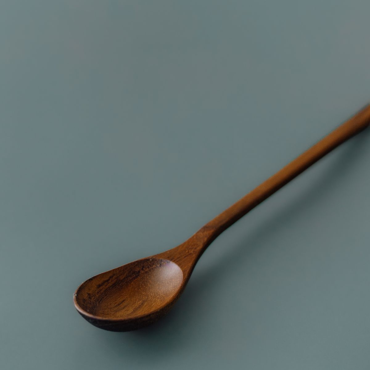 Close-up view showing the natural teak wood grain and oval head of Yompai's handcrafted wooden parfait spoon