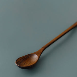 Close-up view showing the natural teak wood grain and oval head of Yompai's handcrafted wooden parfait spoon