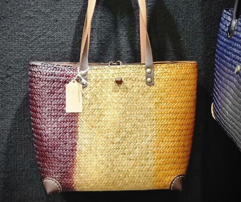 Close-up of a handcrafted three-toned woven bag made from natural sea grass, showing the high-quality burgundy and honey-colored fiber patterns and durable leather handle attachments.
