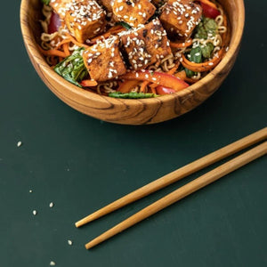 Handcrafted wooden chopsticks ready to be used to eat noodles in a bowl