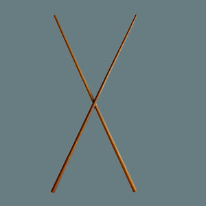 Extra long wooden cooking chopsticks crossing in an X shape against a solid slate blue-gray background.