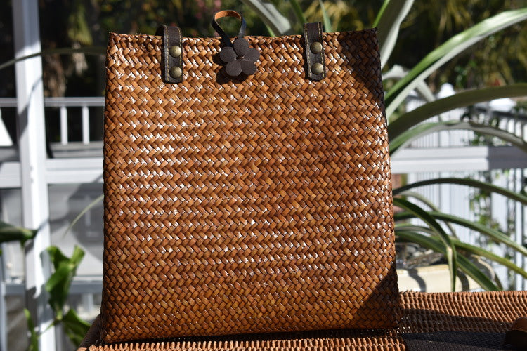handcrafted wooden krajood bag that is sitting on a table. It has leather handles and a flower shaped clasp